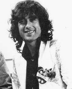 an old black and white photo of a man with long curly hair wearing a jacket