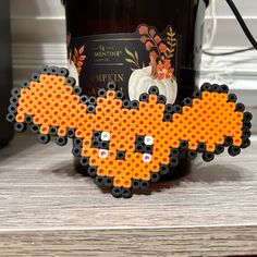 an orange and black beaded animal next to a wine bottle