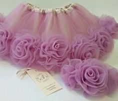 a pink tutu skirt with flowers on it and a tag attached to the bottom