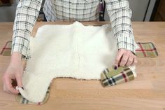 a woman in plaid shirt making rugs on wooden table