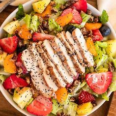 a salad with chicken, strawberries, pineapples and other fruits in it