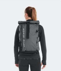 the back view of a woman wearing a grey and black backpack with white lettering on it