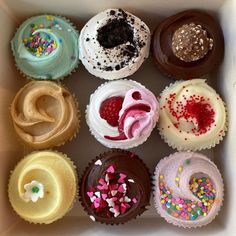 a box filled with lots of different colored cupcakes