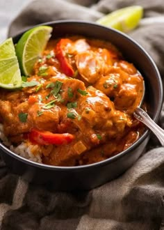 a close up of a bowl of food with rice and limes on the side