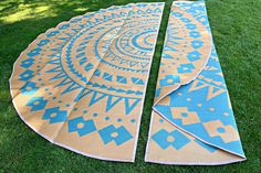 two blue and yellow rugs laying on the grass