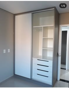 an empty room with white closets and drawers on the wall, in front of a mirror