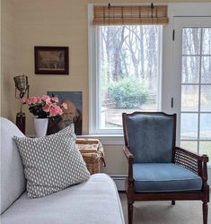 a living room with a couch, chair and large window in it's corner