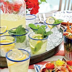 several glasses filled with lemonade and mint garnish on top of an ice tray