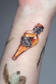 a small tattoo on the wrist of a person with an orange bottle in it's left arm