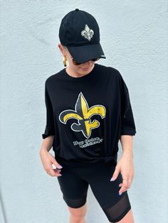 This shirt puts a spin on the classic fleur de lis. It features a Fleur de Lis that is half black/half gold. Perfect for any Saints game! Product comes in Black and in sizes S to XXL. Black Crew Neck Tops For Game Day, Black Crew Neck Tops For Fan Apparel, Black Fan Apparel Tops For Game Day, Black Short Sleeve Fan Merchandise Tops, Black Fan Apparel Top For Game Day, New Orleans Saints Clothing, Lsu Fleur De Lis, New Orleans Saints Shirts, Saints Game