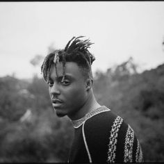 a black and white photo of a man with dreadlocks on his head looking at the camera