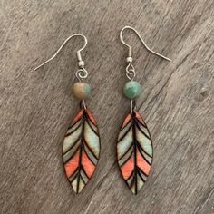 two pairs of earrings with colorful leaves and beaded beads on wooden background, close up