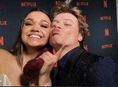 a man and woman posing for a photo in front of netflix's red carpet