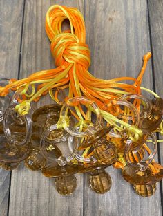 orange and yellow cords are tied to glass goblets on a wooden table with wood planks