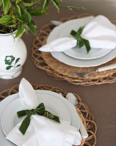 the table is set with white plates and napkins, green leaves on each plate