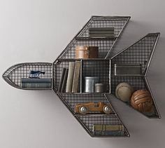 an airplane shaped shelf with books and other items on it's sides, hanging from the wall