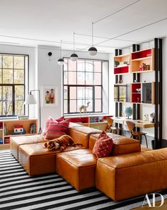 a living room filled with lots of furniture and bookshelves on the wall next to a window