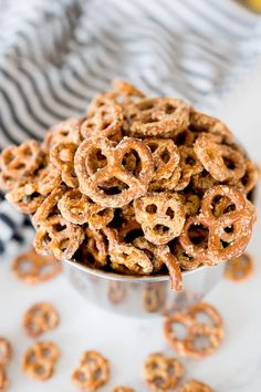 a metal bowl filled with pretzels sitting on top of a white tablecloth