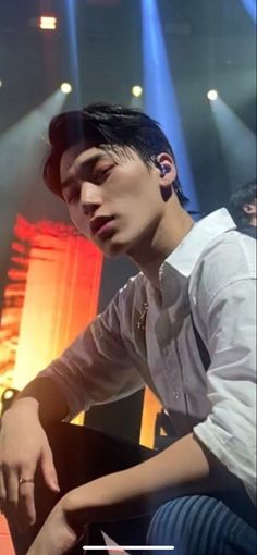 a young man sitting on top of a piano in front of a stage with spotlights