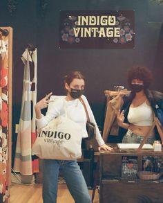 two women standing next to each other in front of a store display with clothing and accessories