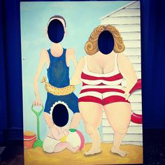 a painting of two women in bathing suits and a child on the beach with a house behind them