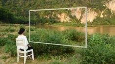 a woman sitting on a chair in front of a mirror that looks like a landscape