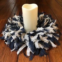 a white candle sitting on top of a wooden floor next to a black and white wreath