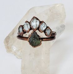 This is a made to order moldavite and herkimer diamond ring set. Each ring is plated in a thick layer of copper, then given an antique finish. The pictures are an example of what you will recieve. Your finished ring will be in the same style as the one pictured. Since the ring is made with natural stones shape and size may vary slighly to the ones pictured. To Purchase choose your ring style preference and ring size. Each ring is hand shaped, electroformed, polished, and then sealed to prevent tarnishing. Message me if you have any questions (: Electroformed Wedding Ring Jewelry, Bohemian Crystal Ring With Raw Stone As Gift, Mystical Gold Electroformed Jewelry, Green Bohemian Electroformed Jewelry, Luxury Electroformed Ring Jewelry, Luxury Nature-inspired Electroformed Jewelry, Electroformed Ring, Herkimer Diamond Ring, Raw Stone Ring