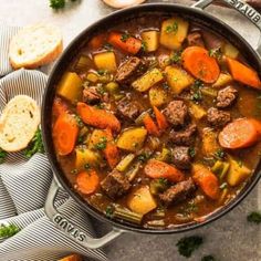 a pot full of stew with carrots, potatoes and meat in it on a table