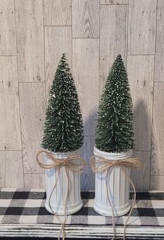 two small christmas trees in white ceramic pots