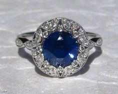 an oval shaped blue sapphire and diamond ring on a white tablecloth with diamonds around it