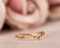 a close up of a gold ring on a white surface with flowers in the background