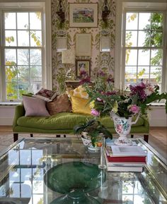 a living room filled with lots of furniture and flowers on top of a glass table