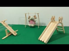 a wooden swing set with an elephant doll next to it and another toy in the background