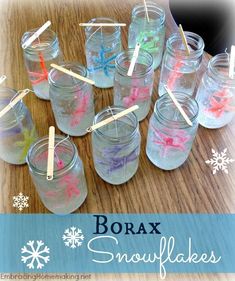 snowflakes are in glass jars with toothpicks sticking out of the top