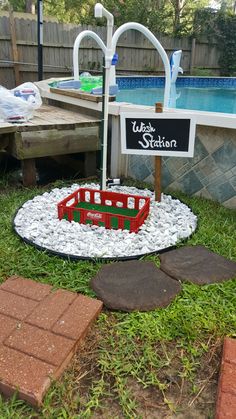 a toy train set sitting in the grass next to a pool with a sign on it