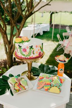 a table topped with a cake covered in icing next to a plate of cookies