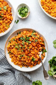 two bowls filled with rice, beans and cilantro on top of a table