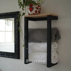 a shelf with towels and a mirror on the wall above it that has a potted plant next to it