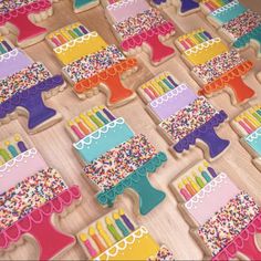 many decorated cookies on a table with sprinkles and candles in the shape of cakes