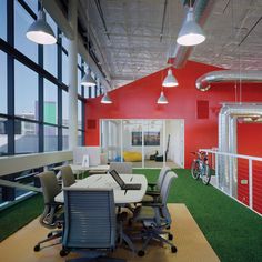 an office with green grass on the floor and red walls, along with lots of windows