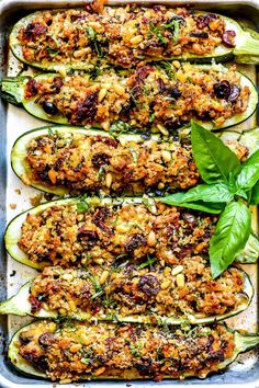 zucchini stuffed with meat and vegetables in a baking pan, garnished with fresh basil leaves