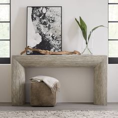 a white table with a plant and some pictures on the wall in front of it