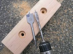 tools are laying on the ground next to a piece of wood with holes in it