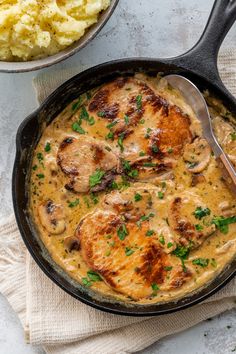 a skillet filled with chicken and gravy next to a bowl of mashed potatoes