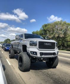 a large white truck driving down a street next to other cars on the side of the road