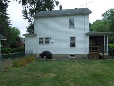 a white house sitting on top of a lush green field next to a fenced in yard