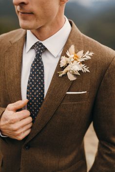 a man wearing a suit and tie with a flower on his lapel pin,