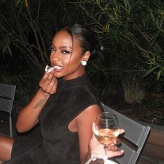 a woman sitting on a bench eating food and drinking wine with a glass in her hand