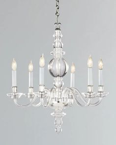 a clear chandelier with six candles hanging from it